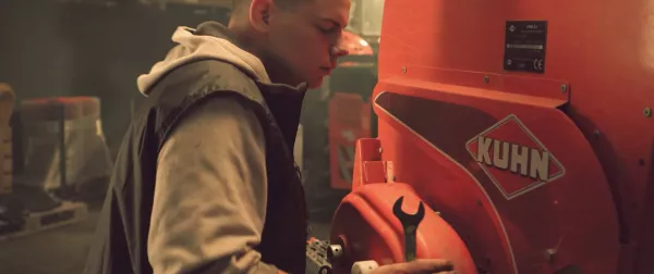 Young farmer fixing his KUHN farm machinery in a shed