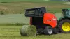 KUHN FB 3130 round baler producing a net bound grass bale in a hilly area.